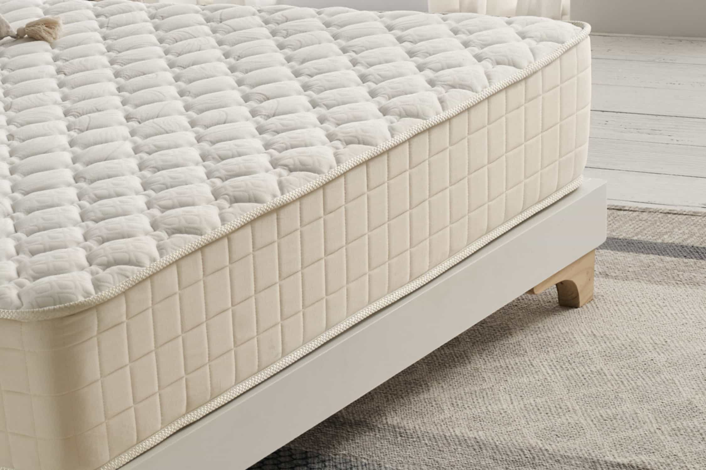 Primer plano de una cama con colchón beige. El colchón tiene un patrón acolchado.
