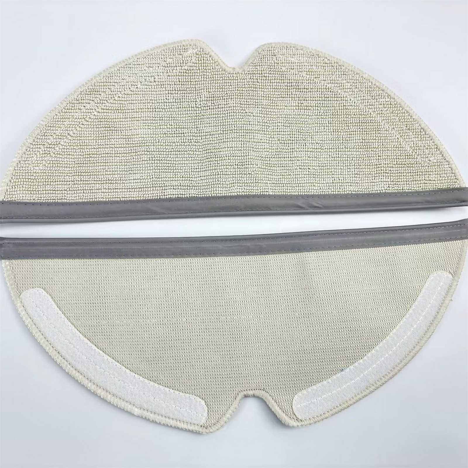 Nahaufnahme eines hellbeigen Wischpads mit grauen Rändern und Klettverschlüssen für einen Staubsauger.