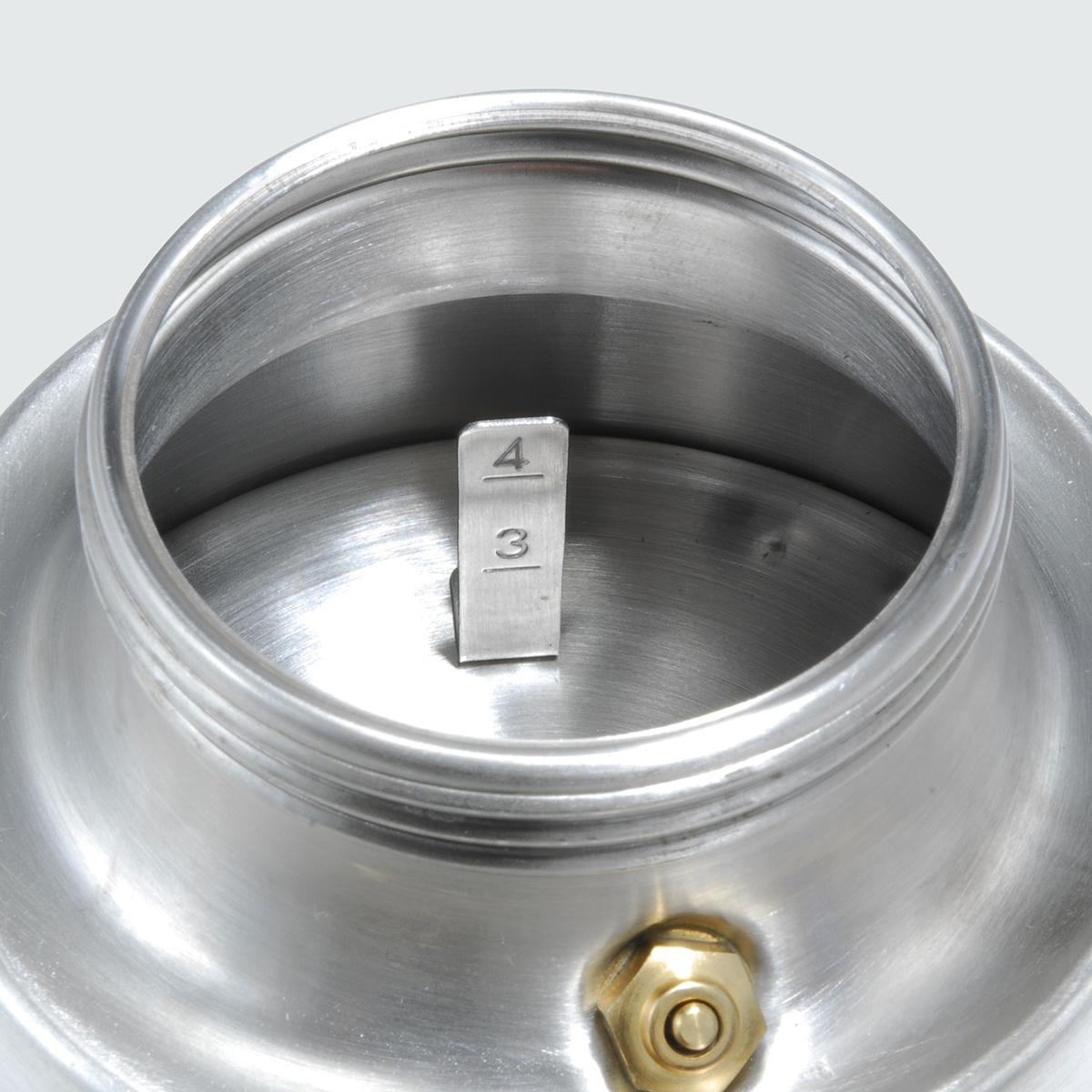 Zbliżenie wnętrza srebrnego ekspresu do kawy z metalowym wskaźnikiem 3 i 4. Widoczna mosiężna śruba.