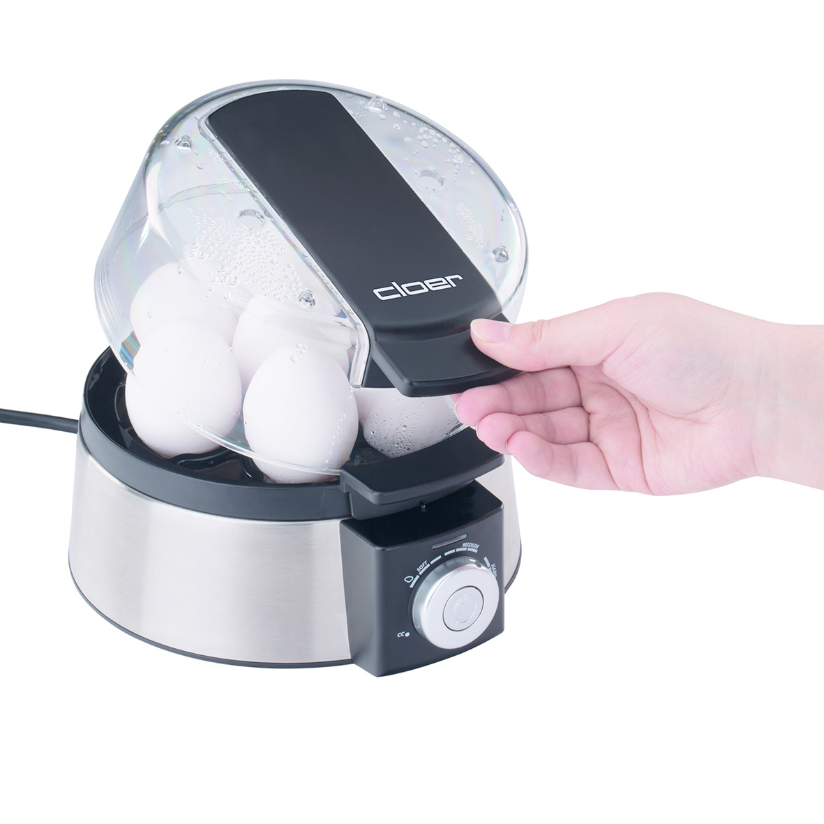 Ręka otwiera garnek do jajek. Pokrywa jest podnoszona, aby odsłonić jajka.