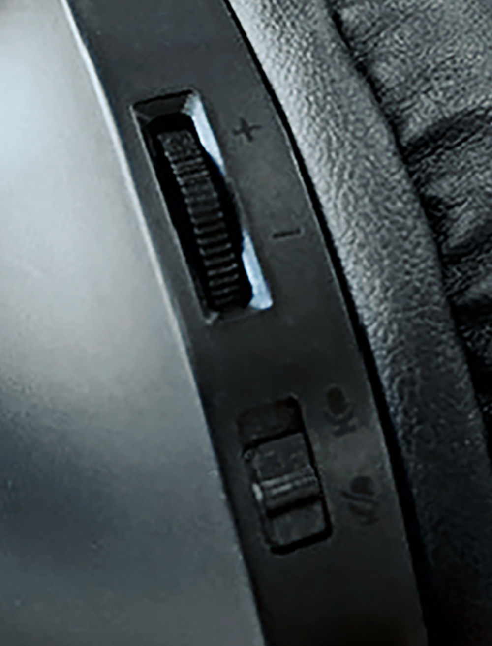 Close-up of a black headset's volume control wheel and buttons.