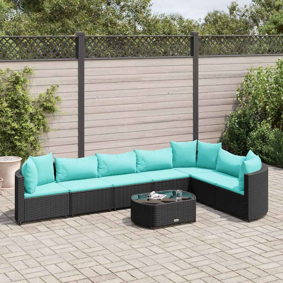 Un set da patio nero con cuscini turchesi. Un tavolo rotondo di fronte.