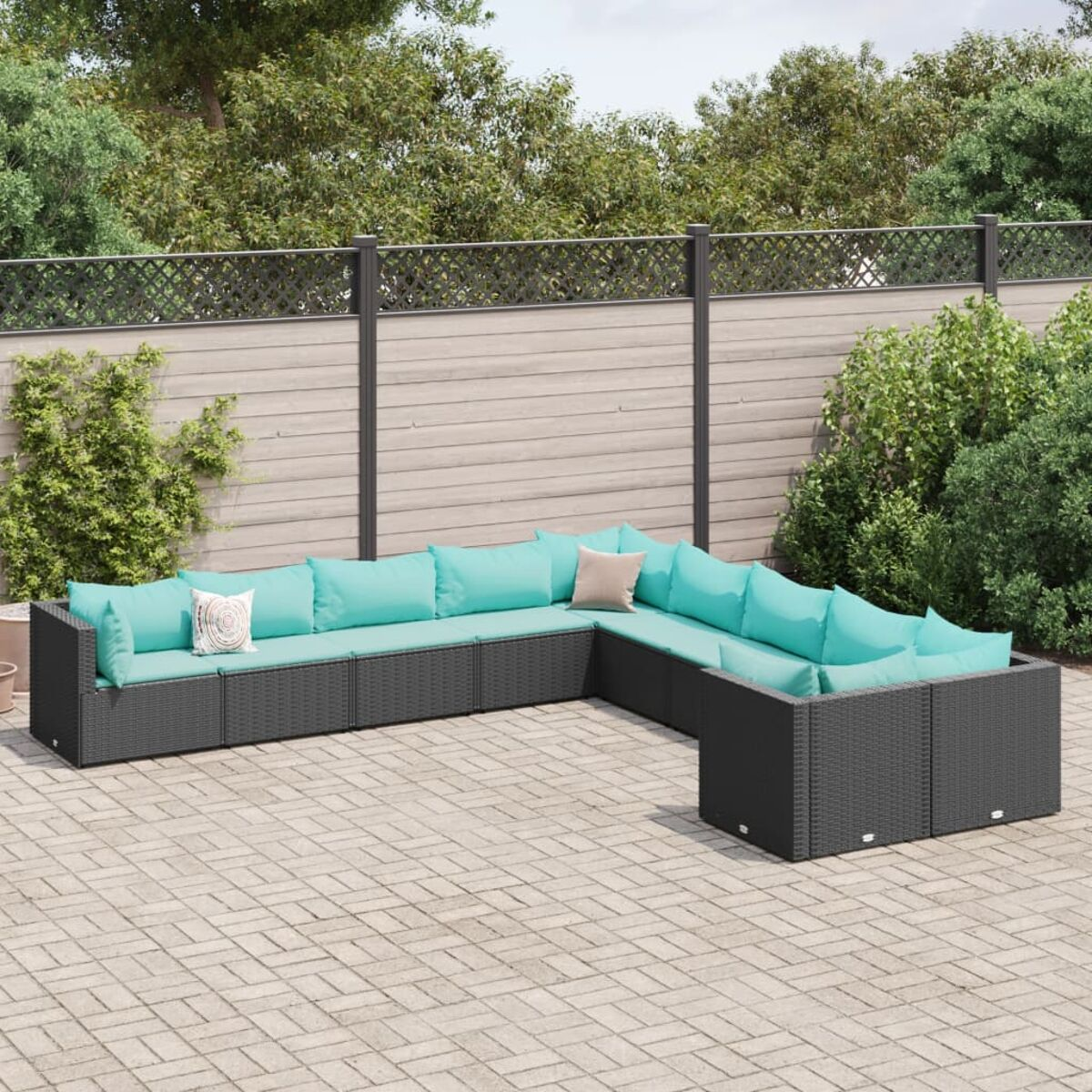 Divano componibile in vimini nero con cuscini azzurri. Su un patio in mattoni con verde.