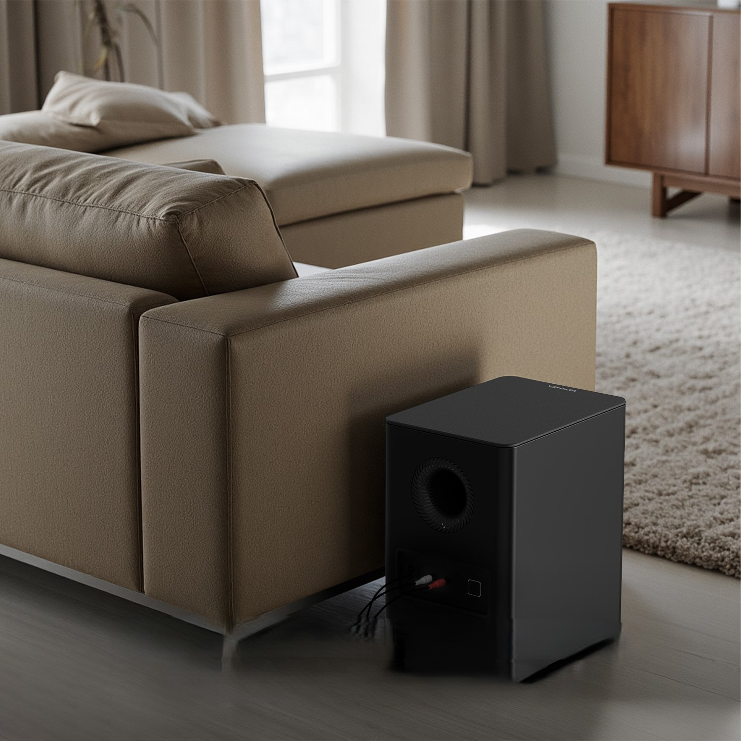 Beżowa kanapa z czarnym subwooferem. Tło obejmuje dywan, okno i drewniane meble.