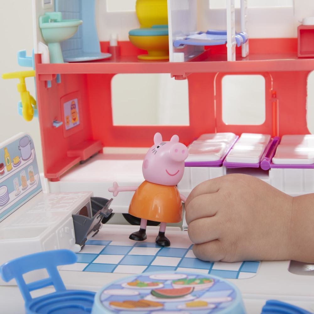 Die Hand eines Kindes greift nach Peppa Wutz Spielzeug in einem Wohnmobil-Spielset, zeigt eine Küche.