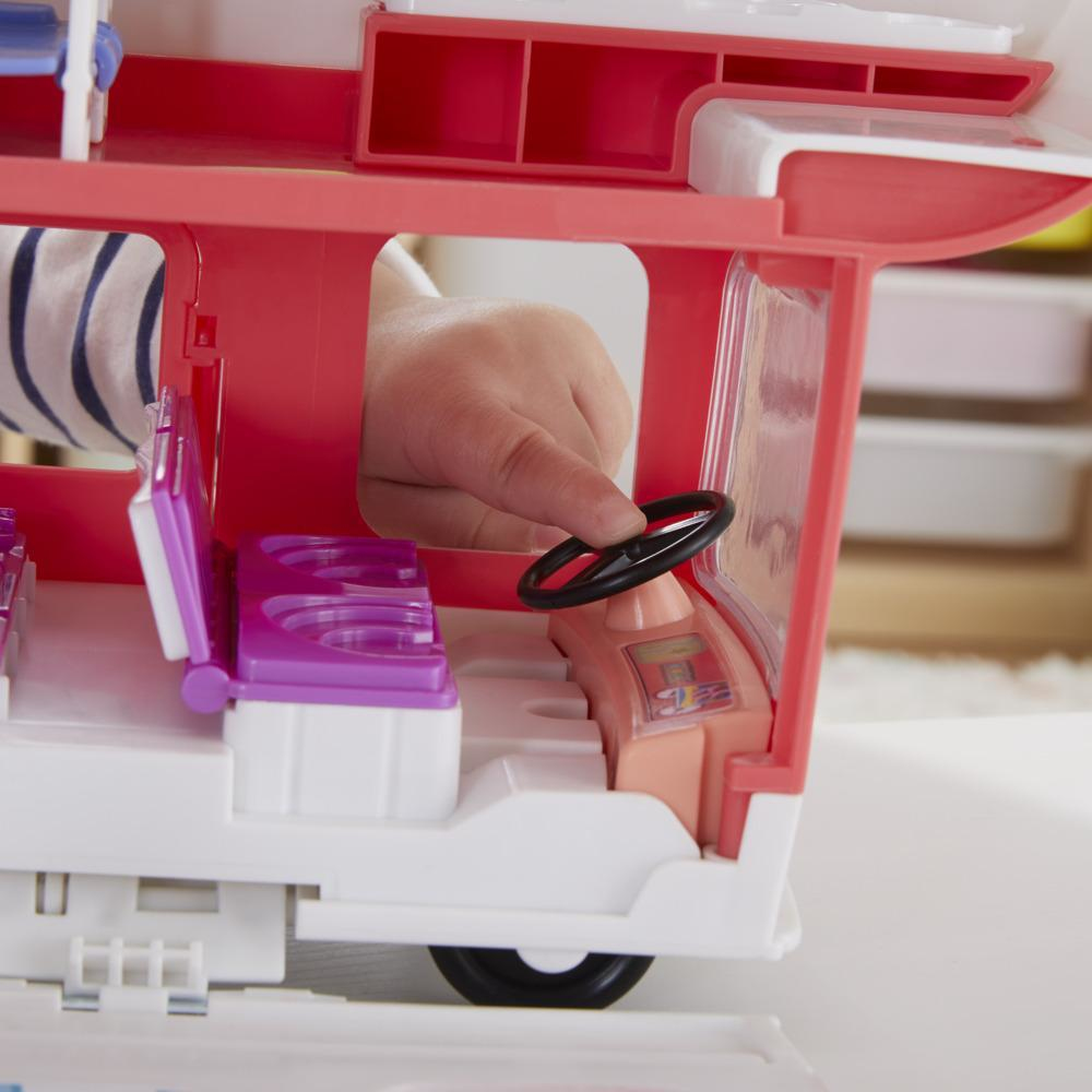 Die Hand eines Kindes berührt ein Lenkrad in einem Spielzeug-Wohnmobil.