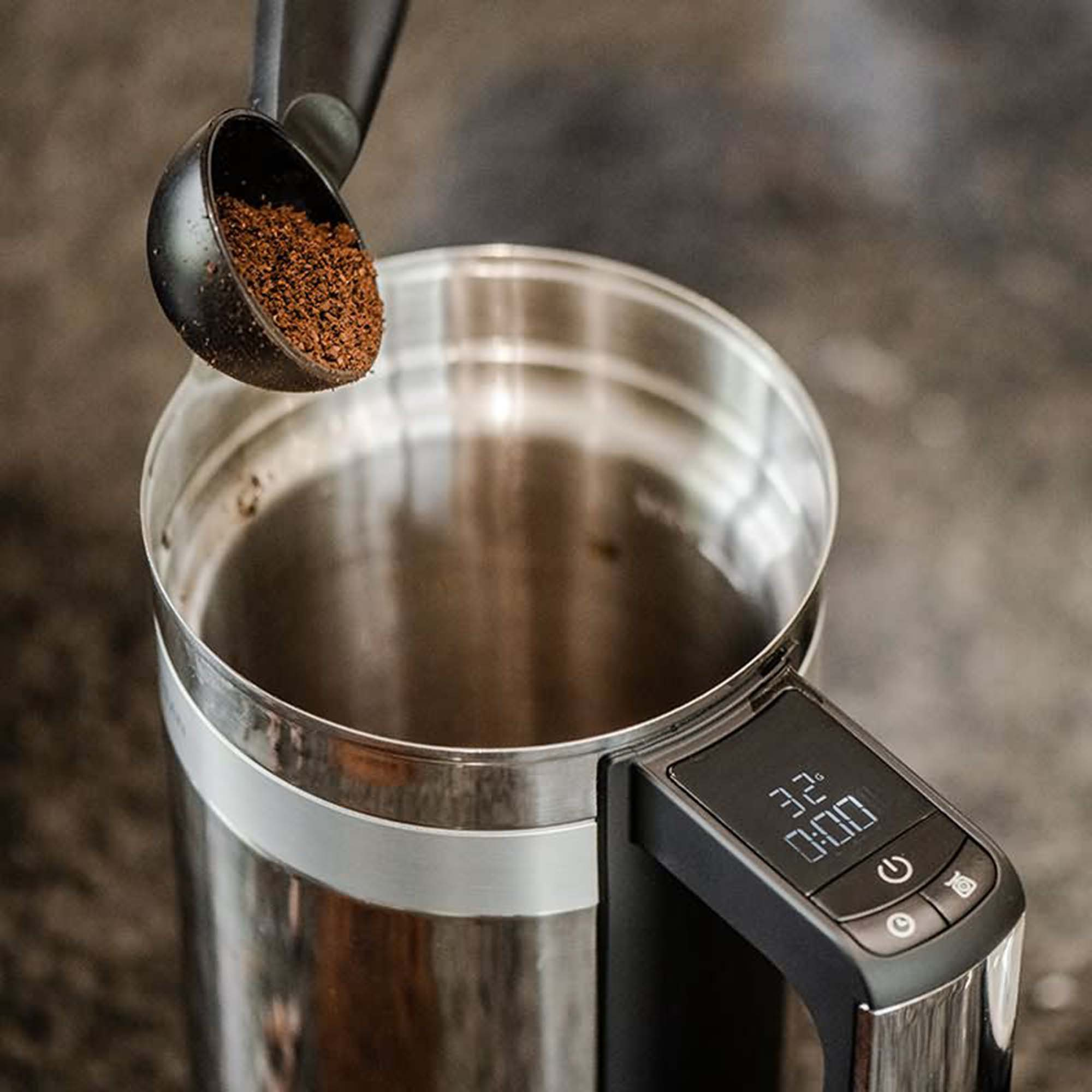 Kaffee wird in einen Edelstahlbehälter gegossen, Digitalanzeige vorhanden.