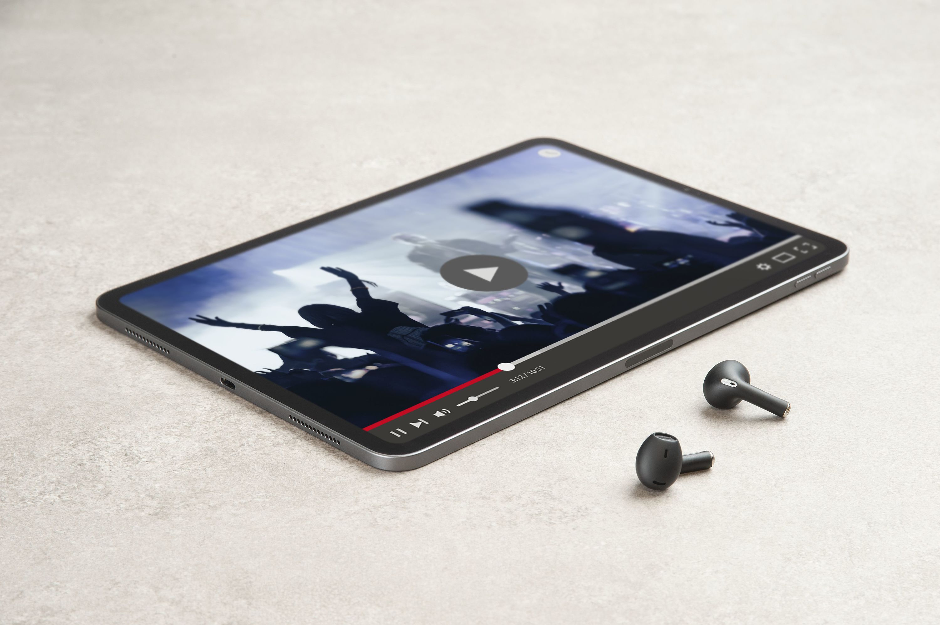 Tablet, das ein Video anzeigt, mit Ohrhörern daneben. Das Tablet liegt auf einer Oberfläche.