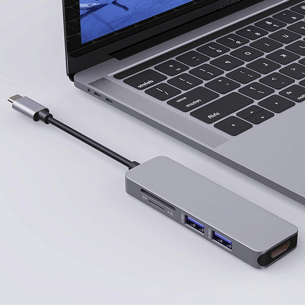 Ein silberner Hub mit USB-Anschlüssen und einem SD-Kartensteckplatz ist mit einem Laptop verbunden.