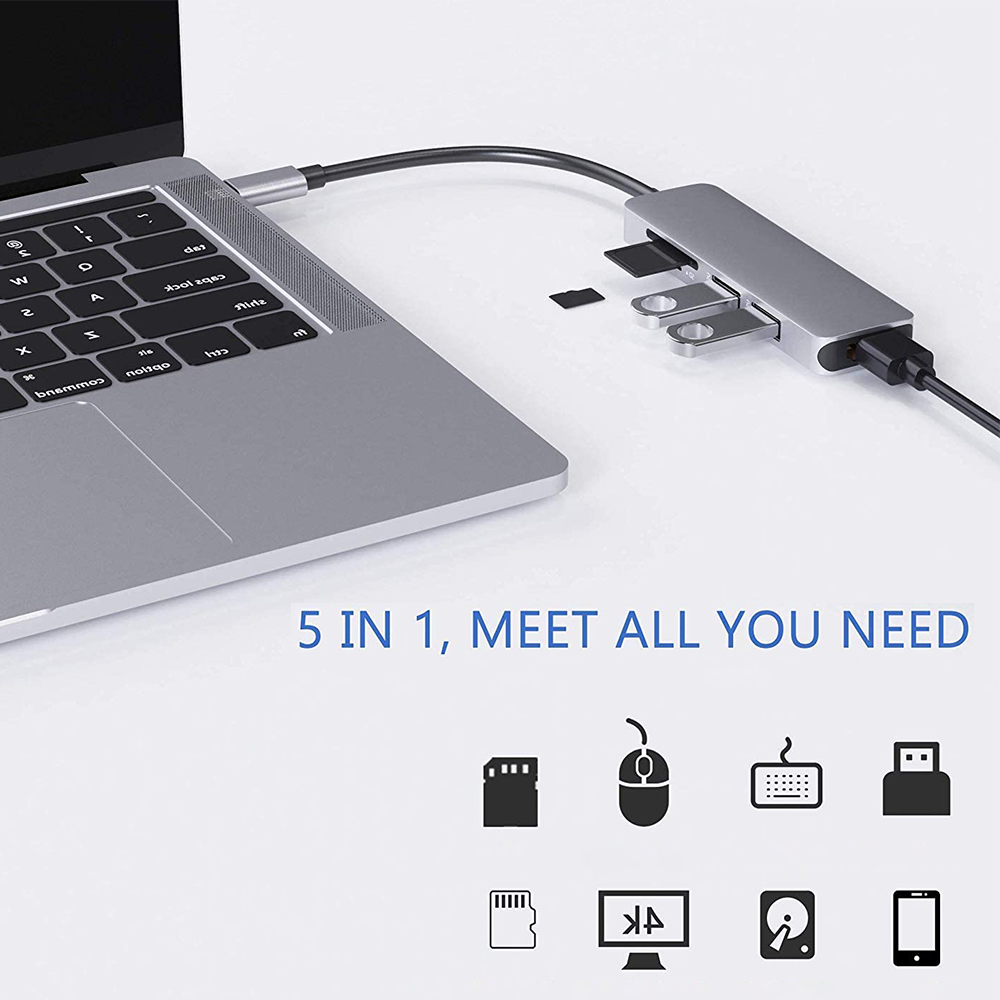 Silberner Laptop mit angeschlossenem USB-Hub, verschiedenen Anschlüssen und Geräten.