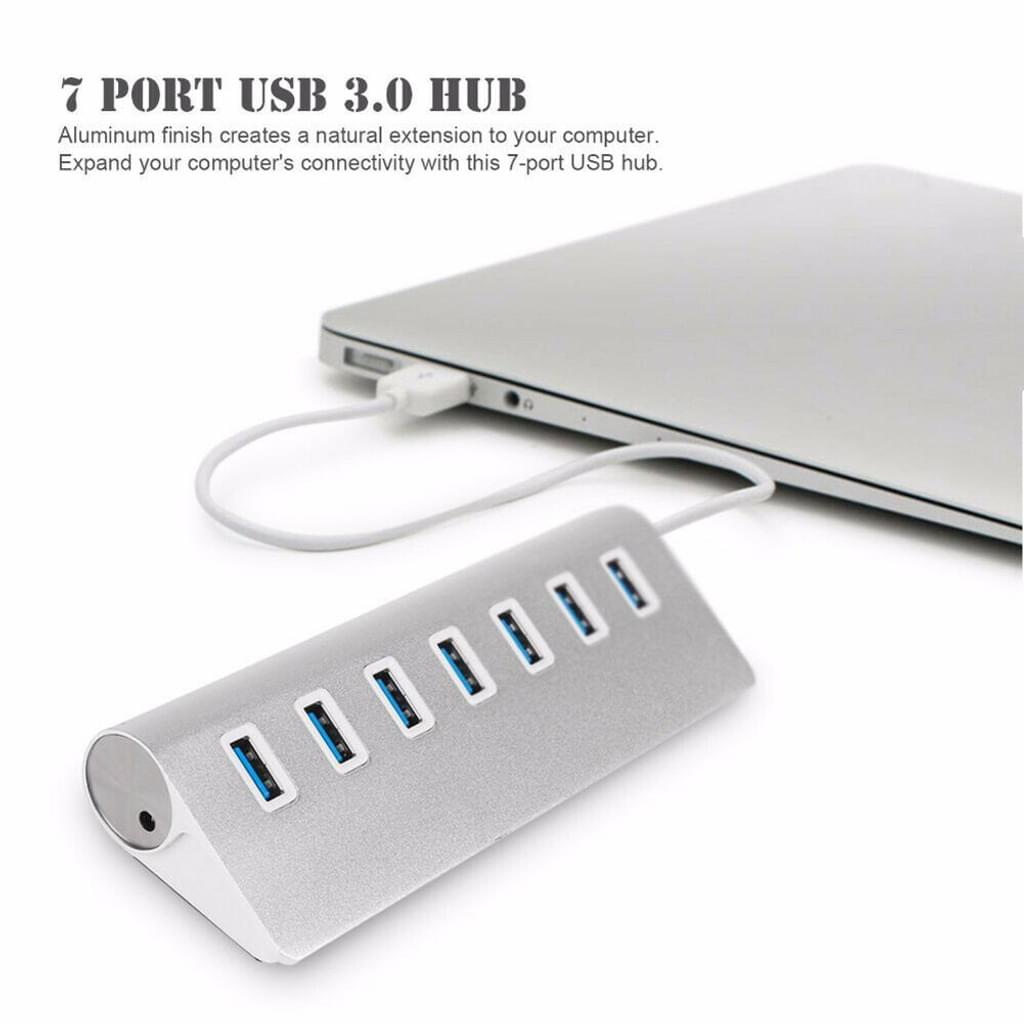 USB-Hub an einen Laptop angeschlossen. Silberner Hub mit sieben blauen Anschlüssen. Weißes Kabel.