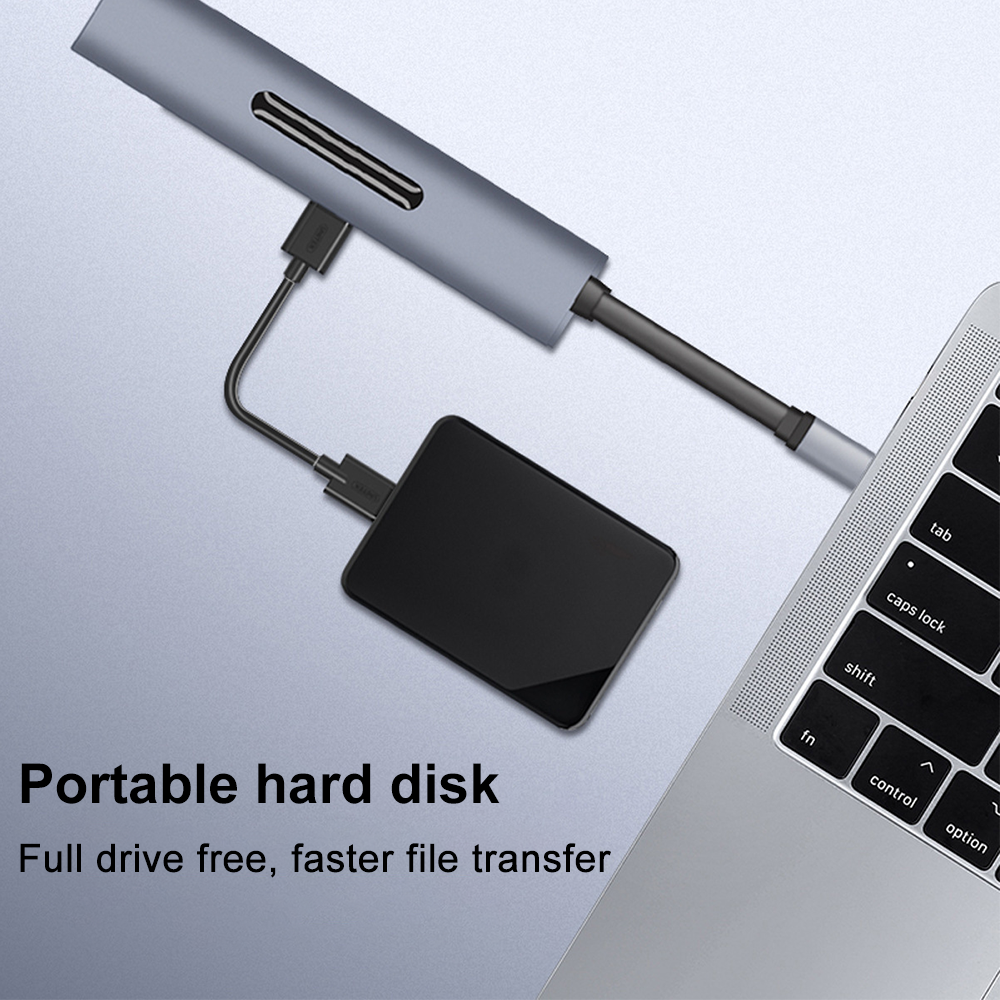 Ein silberner USB-Hub, der mit einem Laptop und einer schwarzen Festplatte verbunden ist.