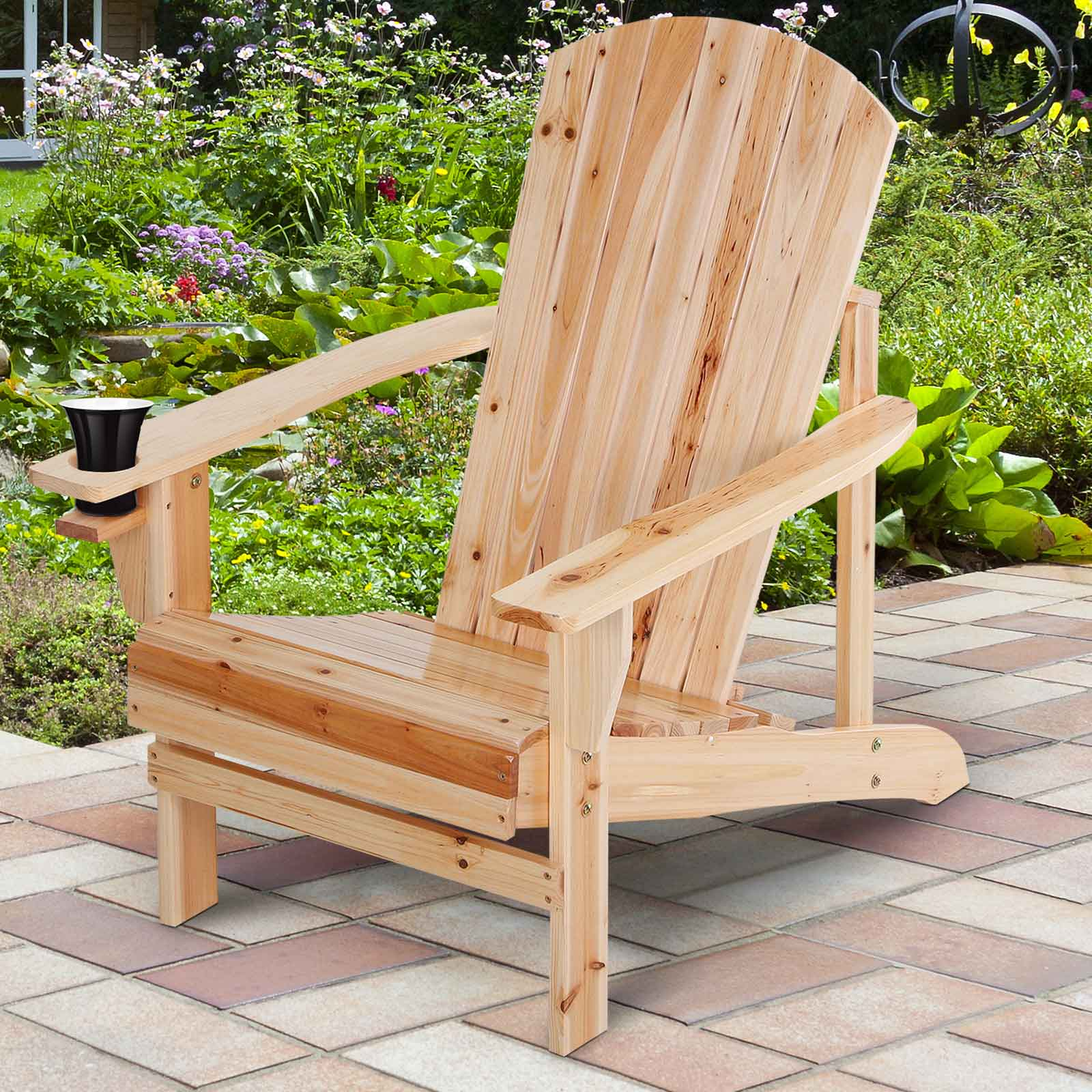 Holz-Adirondack-Stuhl auf einer Ziegelterrasse, mit Getränkehalter. Hintergrund: grüner Garten.