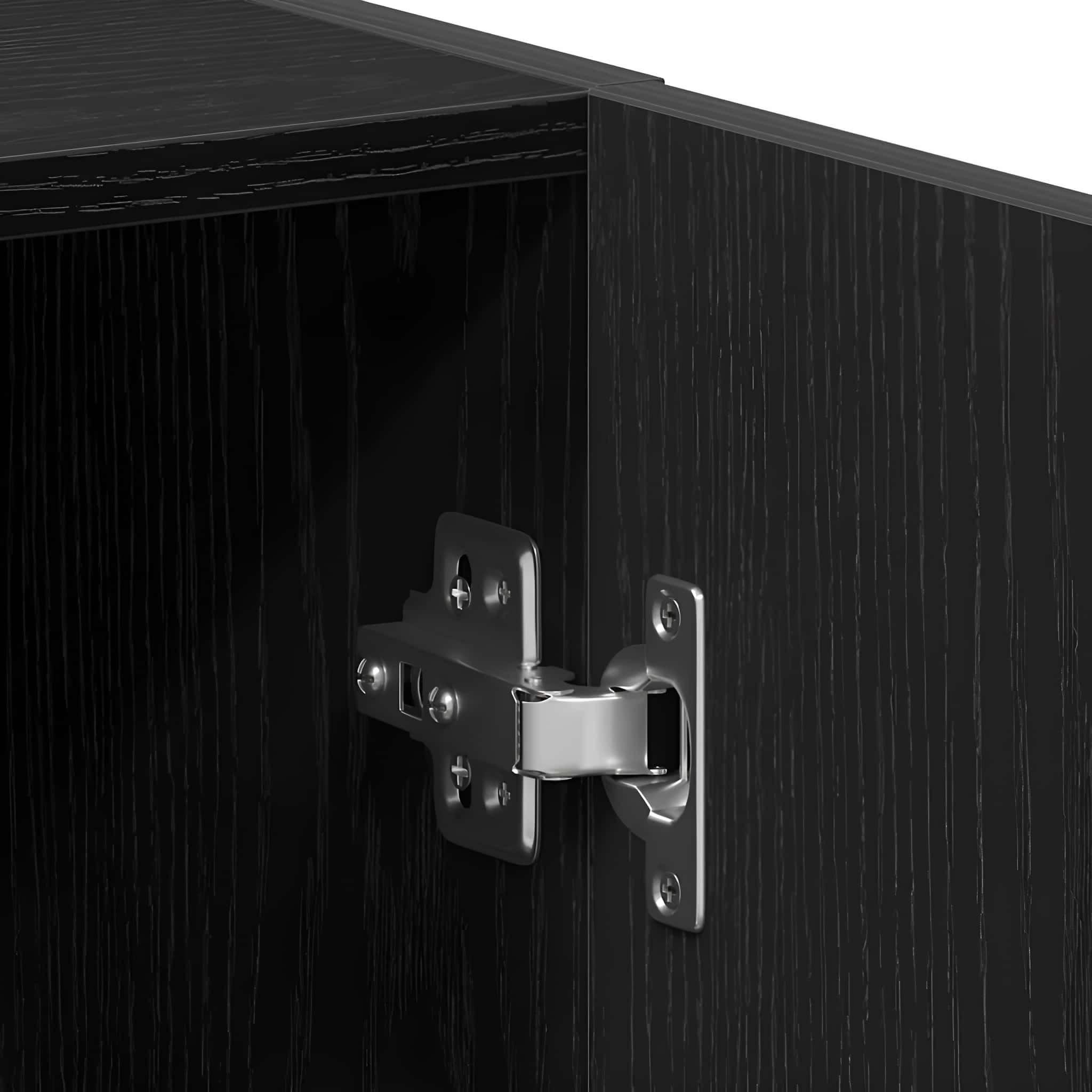 Nahaufnahme eines Metallscharniers an einem schwarzen Holzschrank. Das Scharnier glänzt und ist am Holz befestigt.