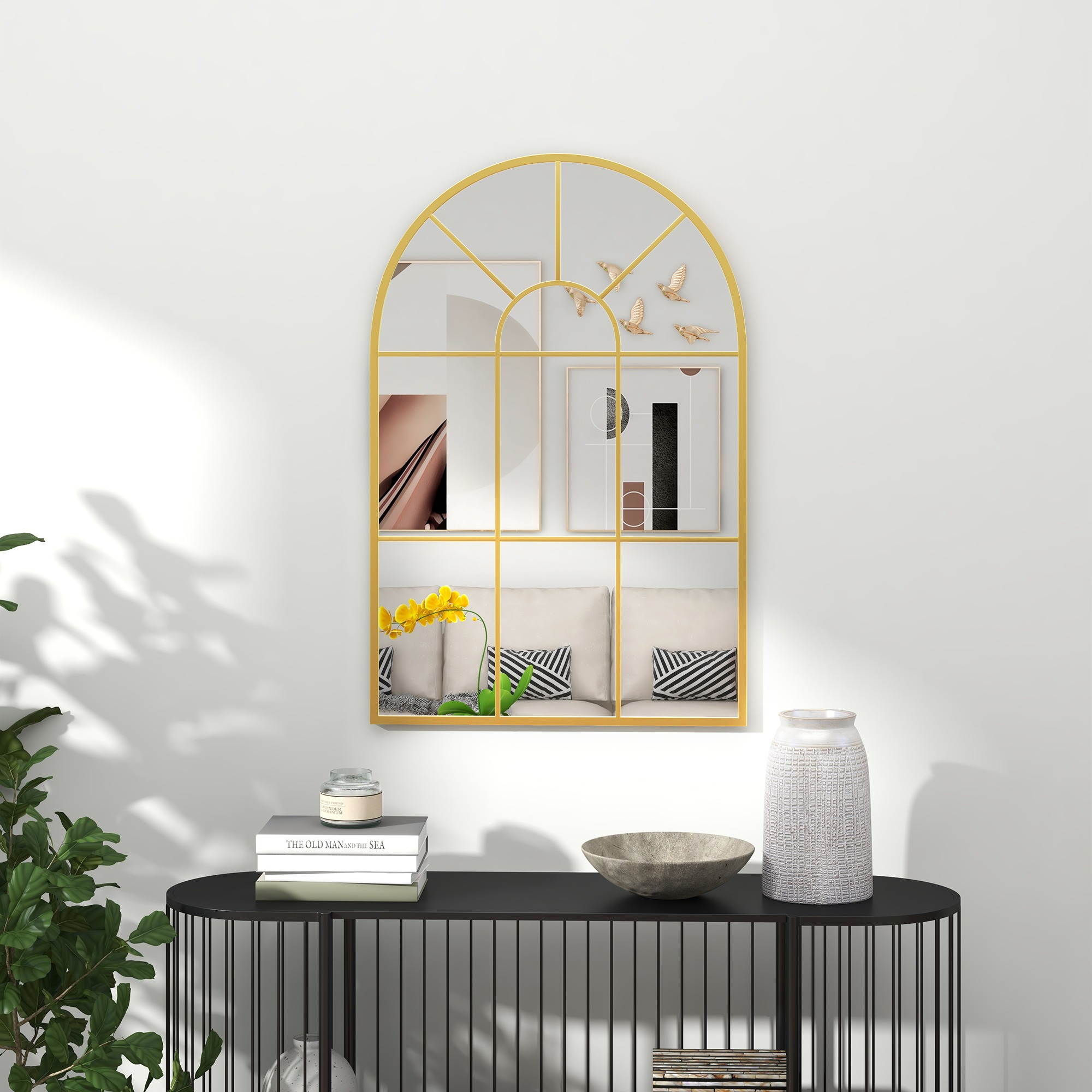 Goldener Bogen-Spiegel mit schwarzem Konsolentisch und weißer Wand. Dekorative Gegenstände auf dem Tisch.