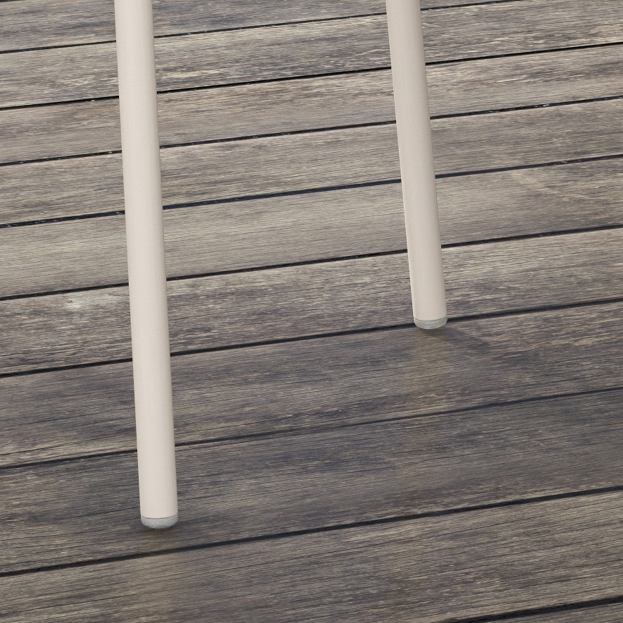 Nahaufnahme der Beine eines hellfarbigen Stuhls auf einem Holzdeck.