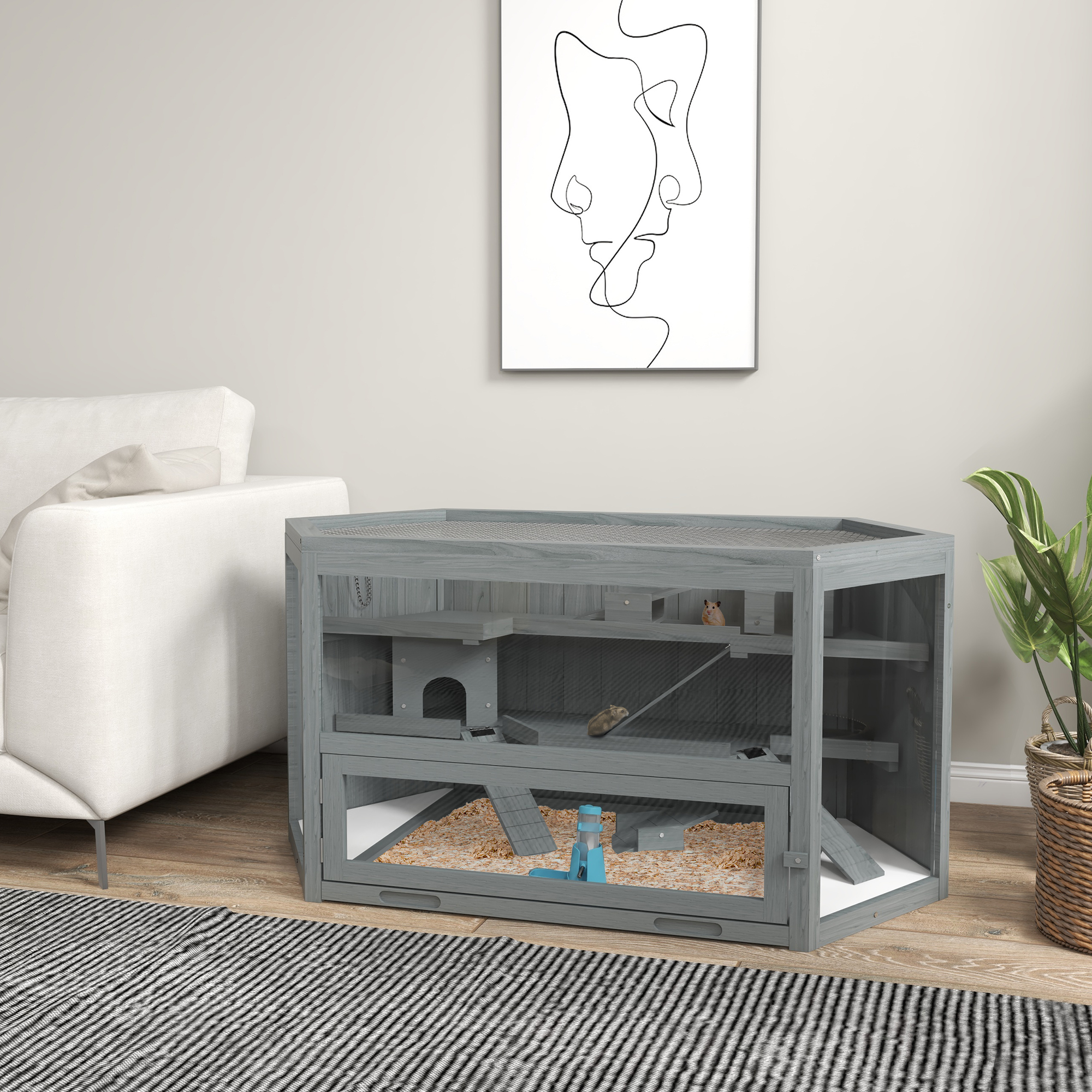 Ein grauer Hamsterkäfig aus Holz mit mehreren Ebenen, Einstreu und einem Hamster, neben einem Sofa.