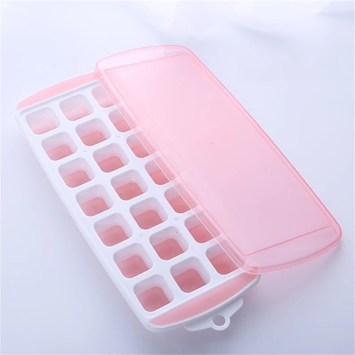 Ein weiß-rosa Eiswürfelbehälter mit einem transparenten rosa Deckel. Das Tablett ist offen, zeigt die Eiswürfelformen.