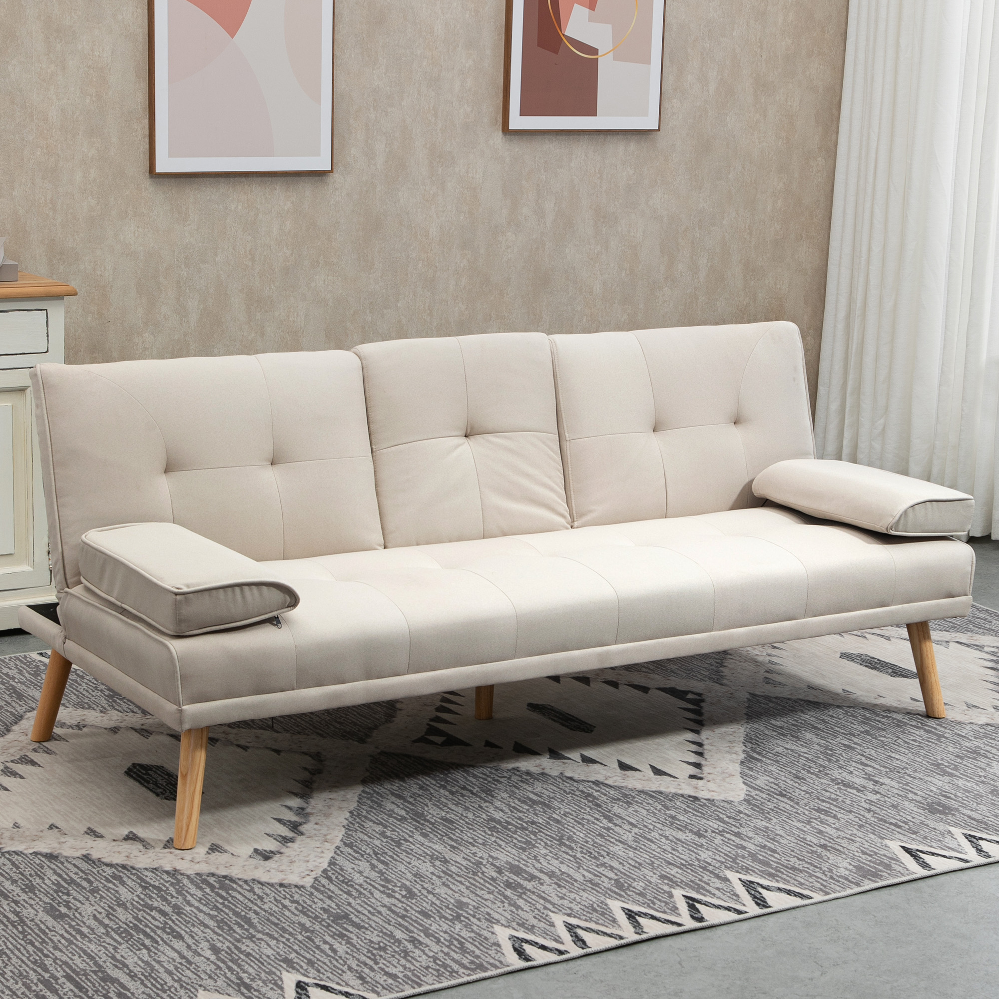 Beiges Stoffsofa mit Holzbeinen auf einem gemusterten Teppich, mit gerahmten Kunstwerken darüber.