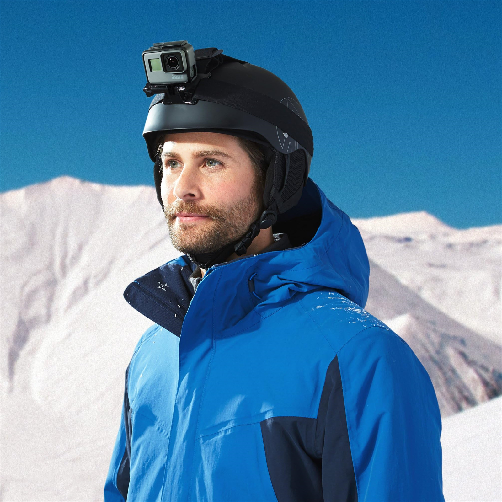 Ein Mann mit einem schwarzen Helm mit einer GoPro-Kamera, der auf einem verschneiten Berg steht.