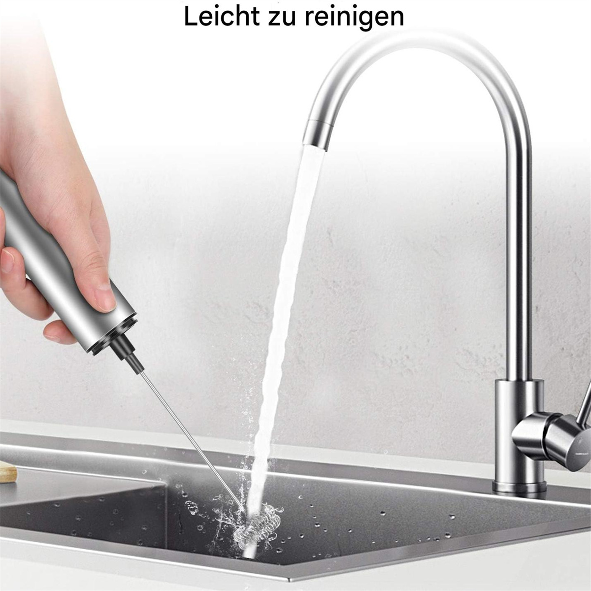 Eine Hand hält einen Milchaufschäumer unter einem Wasserhahn. Das Wasser fließt in ein Waschbecken.