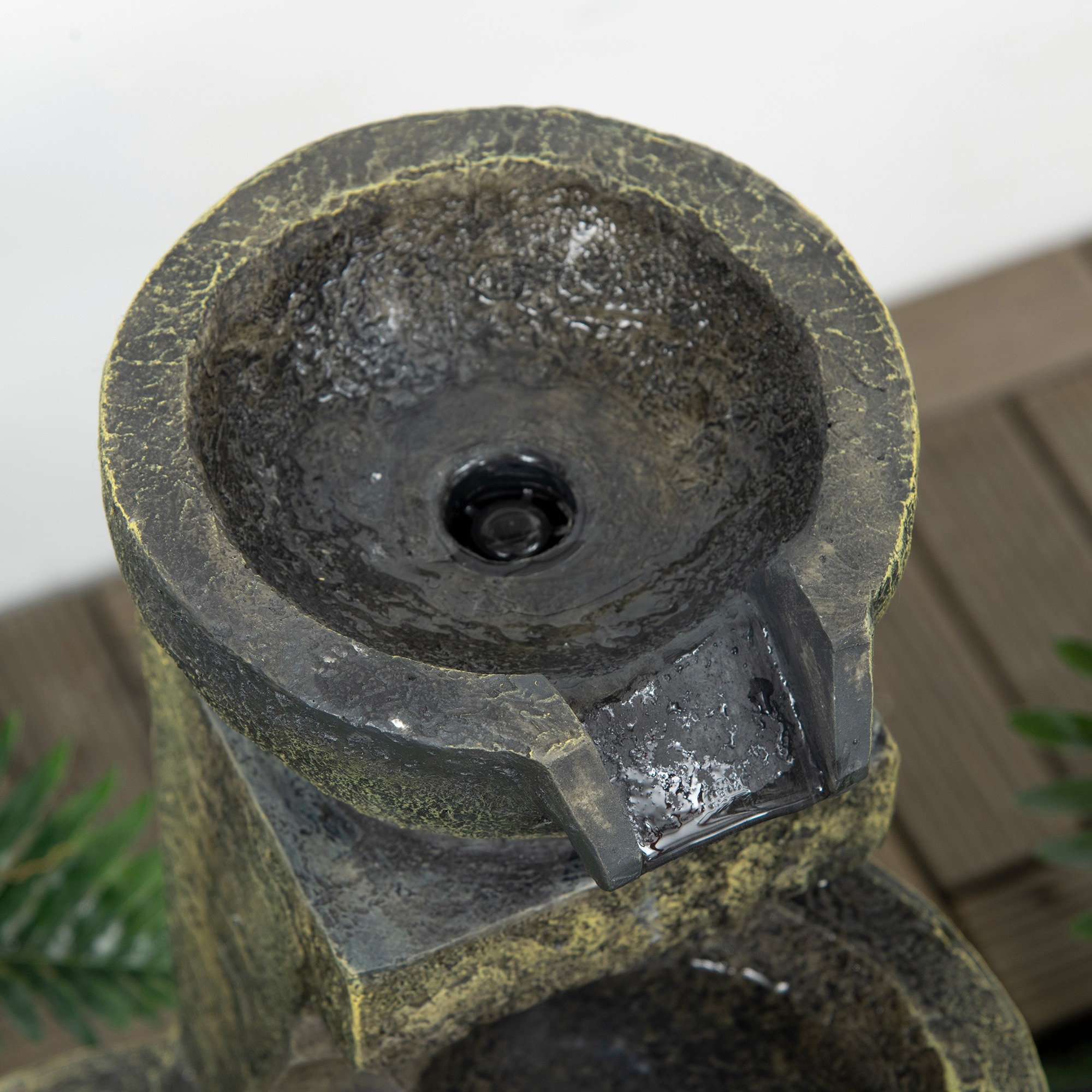 Nahaufnahme einer Steinbrunnen-Schale. Wasser fließt daraus heraus.