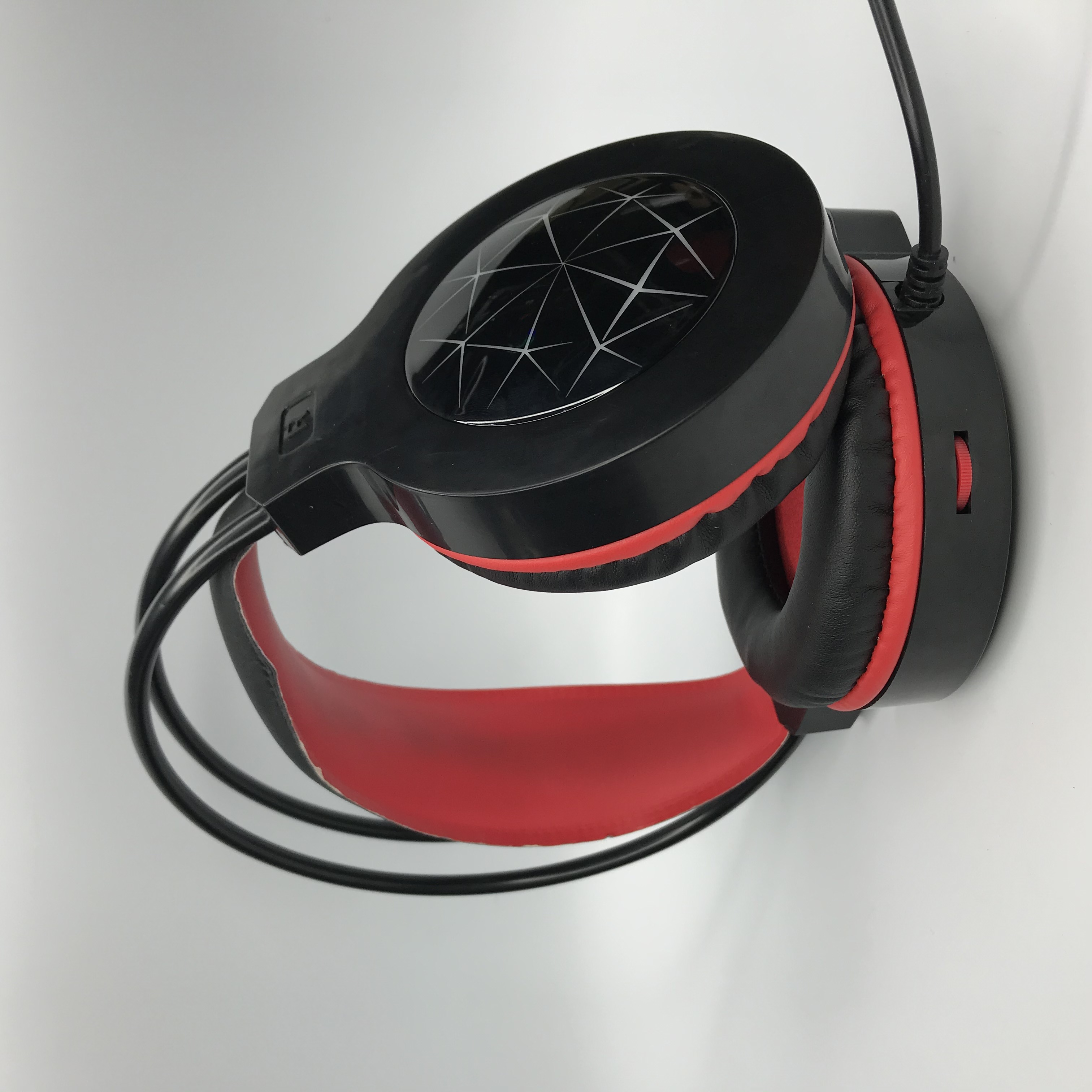 Cuffie da gioco nere e rosse. Cuscinetti e fascia rossa. Padiglioni neri con design geometrico.