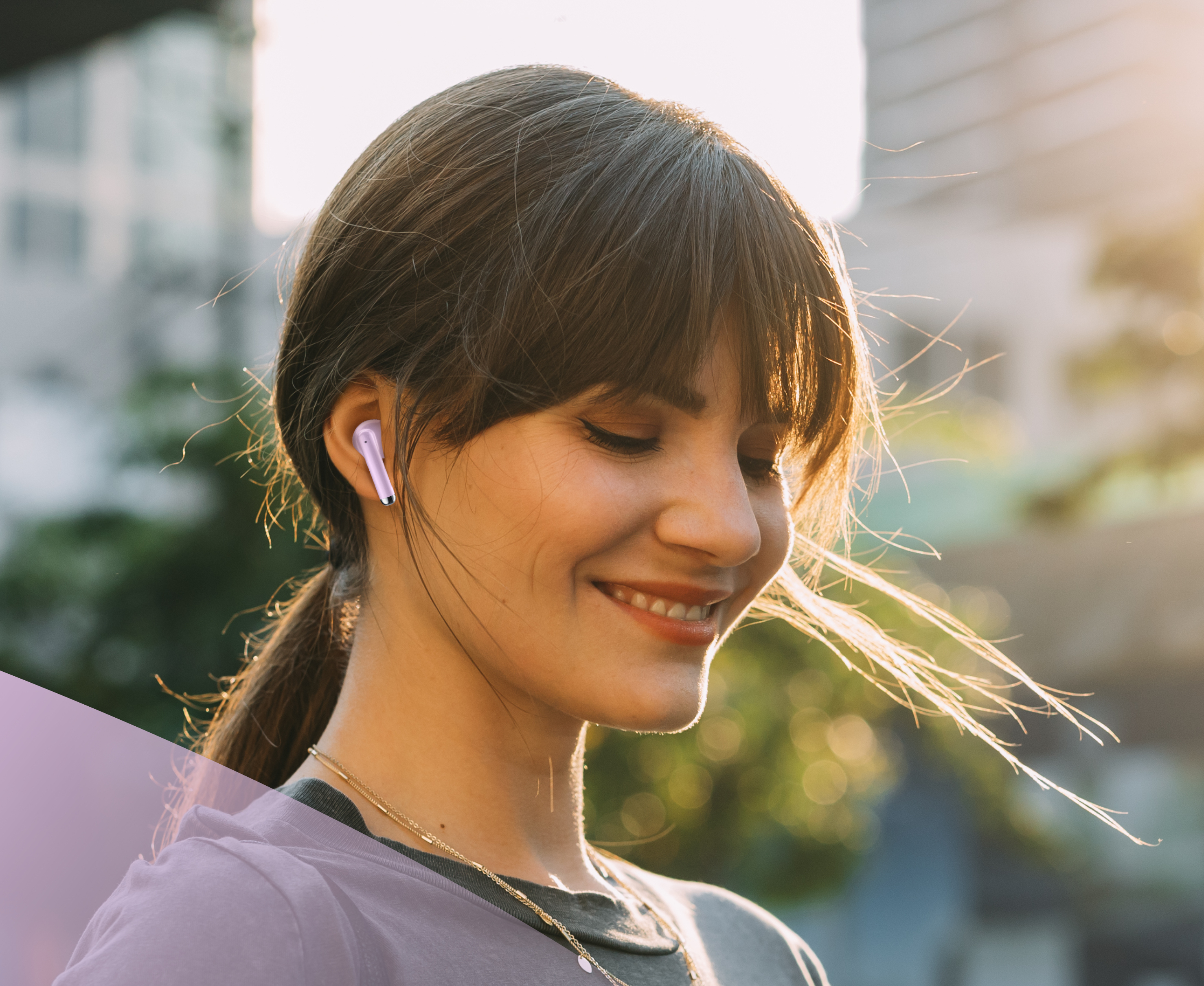 Una donna con auricolari sorride, con uno sfondo sfocato di una città.