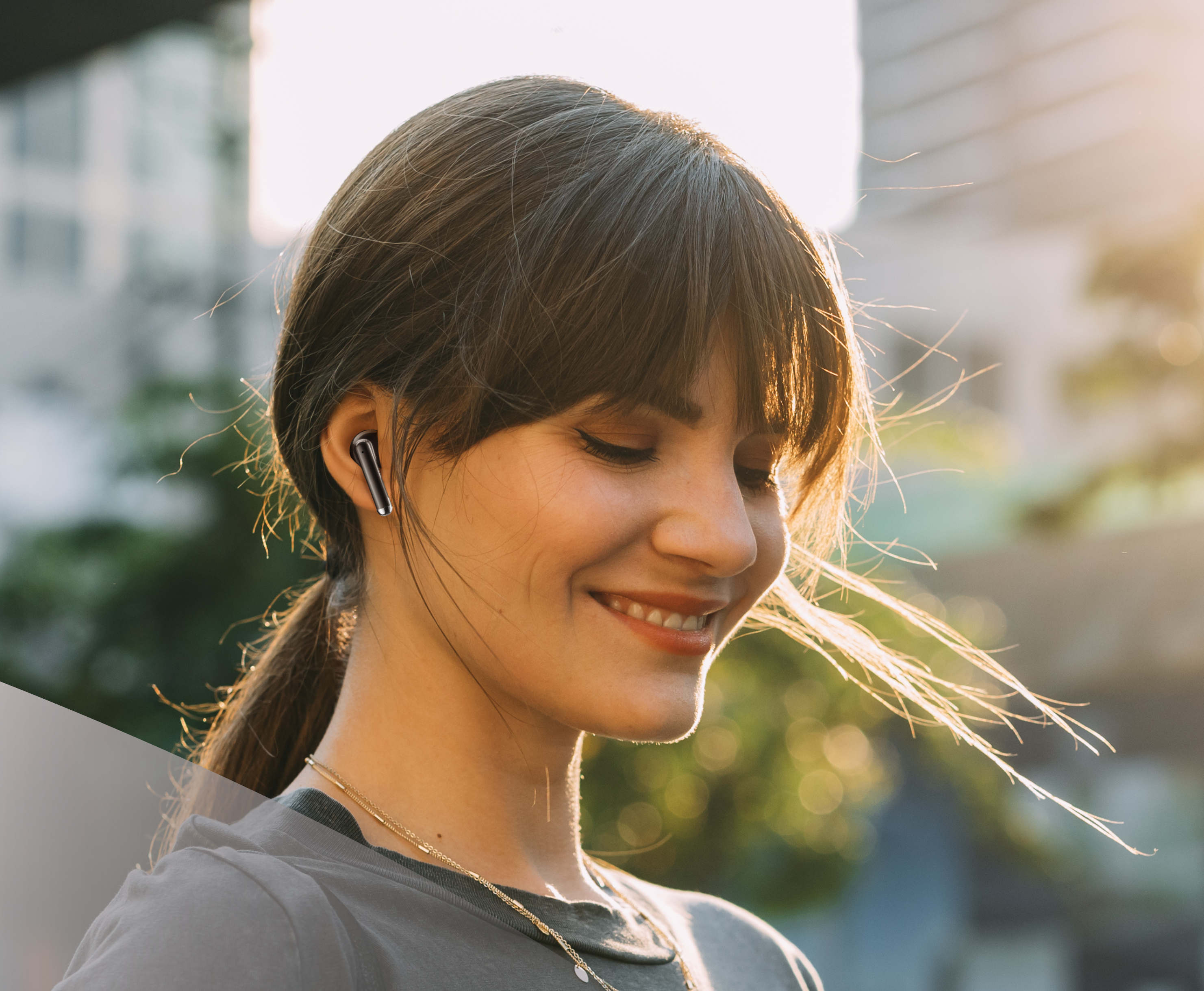Una mujer con auriculares negros, sonriendo con un fondo de una escena urbana.