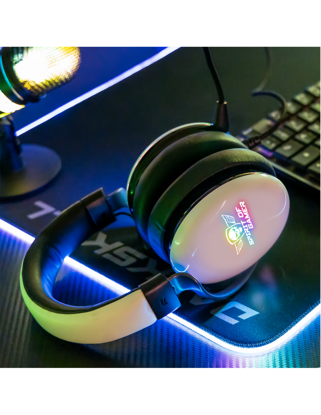 Cuffie da gioco su una scrivania. Cuffie bianche con un logo. Illuminate da una configurazione di gioco.