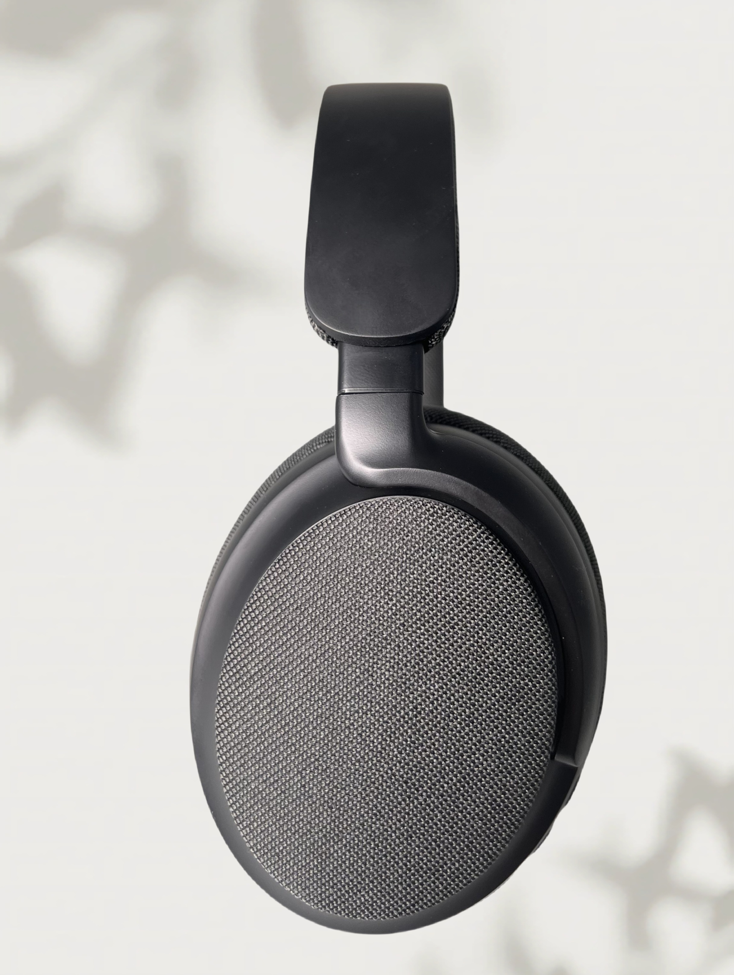Primer plano de auriculares negros desde un lado, mostrando la diadema y el diseño de la copa, sobre fondo blanco.
