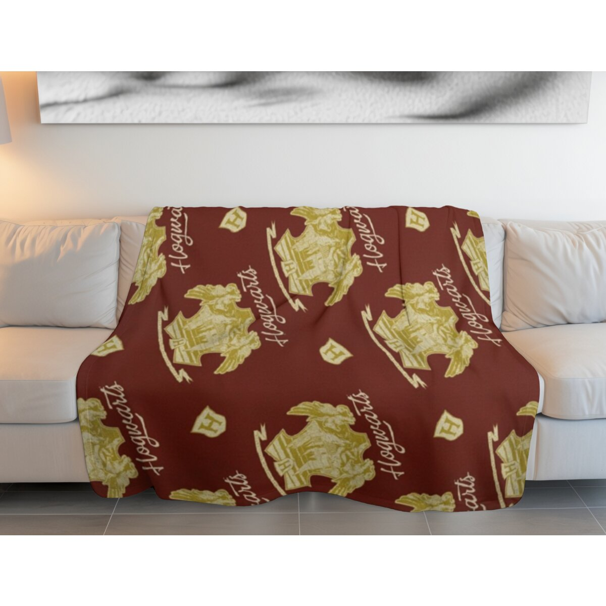 Rote Decke auf weißem Sofa, mit sich wiederholendem Hogwarts-Logo.