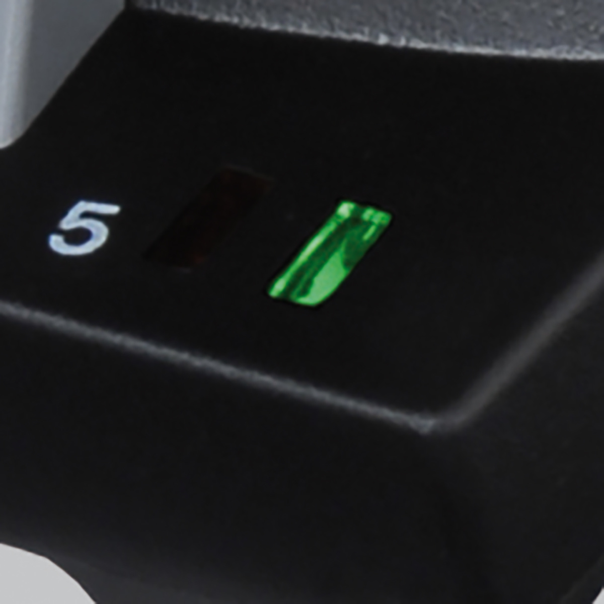 Zbliżenie czarnego obiektu z cyfrą 5 i zielonym światłem. Białe tło.