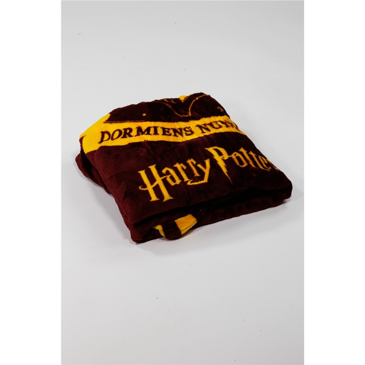 Eine gefaltete kastanienbraune Harry-Potter-Decke mit goldfarbenen Buchstaben.