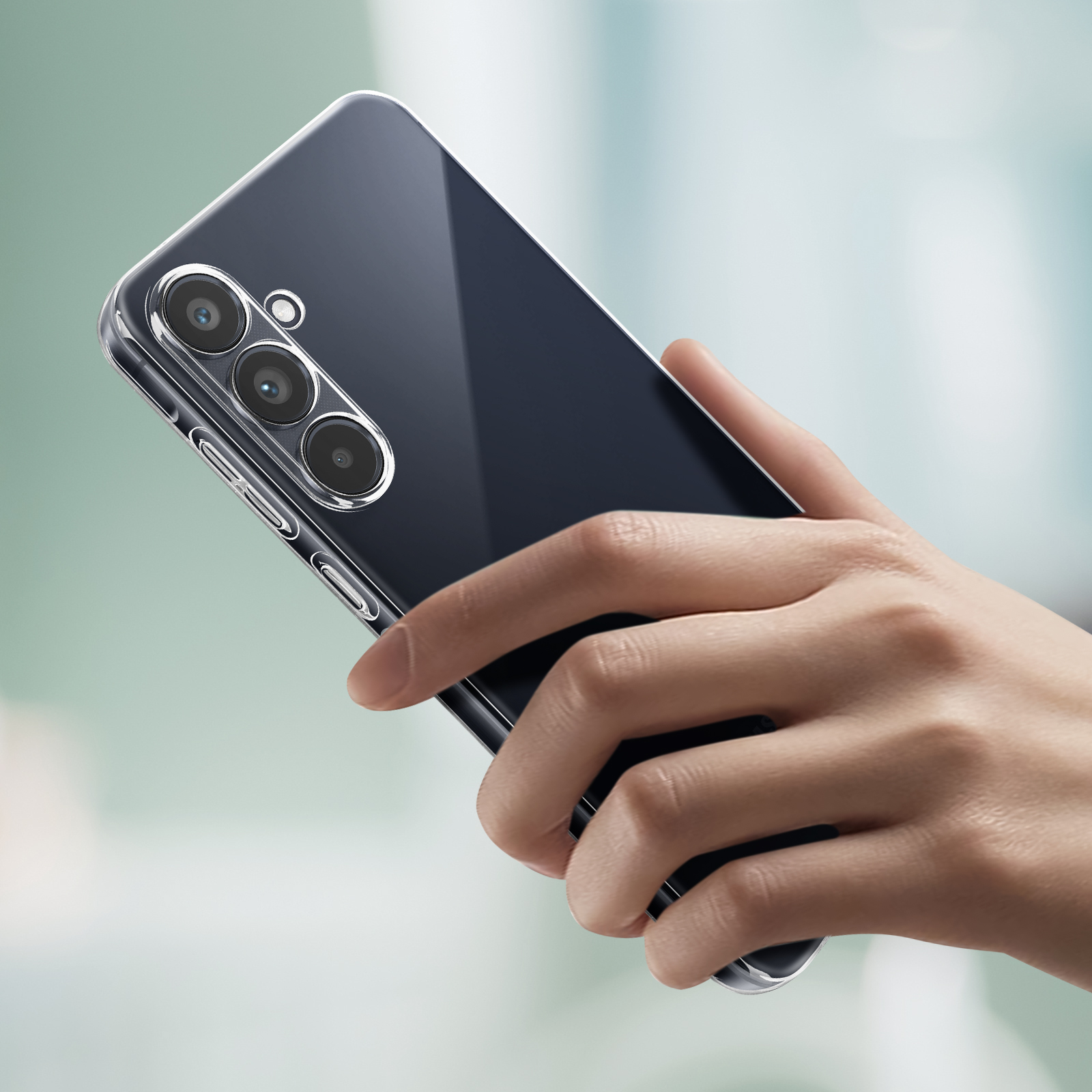 Eine Hand hält eine transparente Handyhülle über einem dunkel gefärbten Telefon. Das Telefon hat drei Kameras.