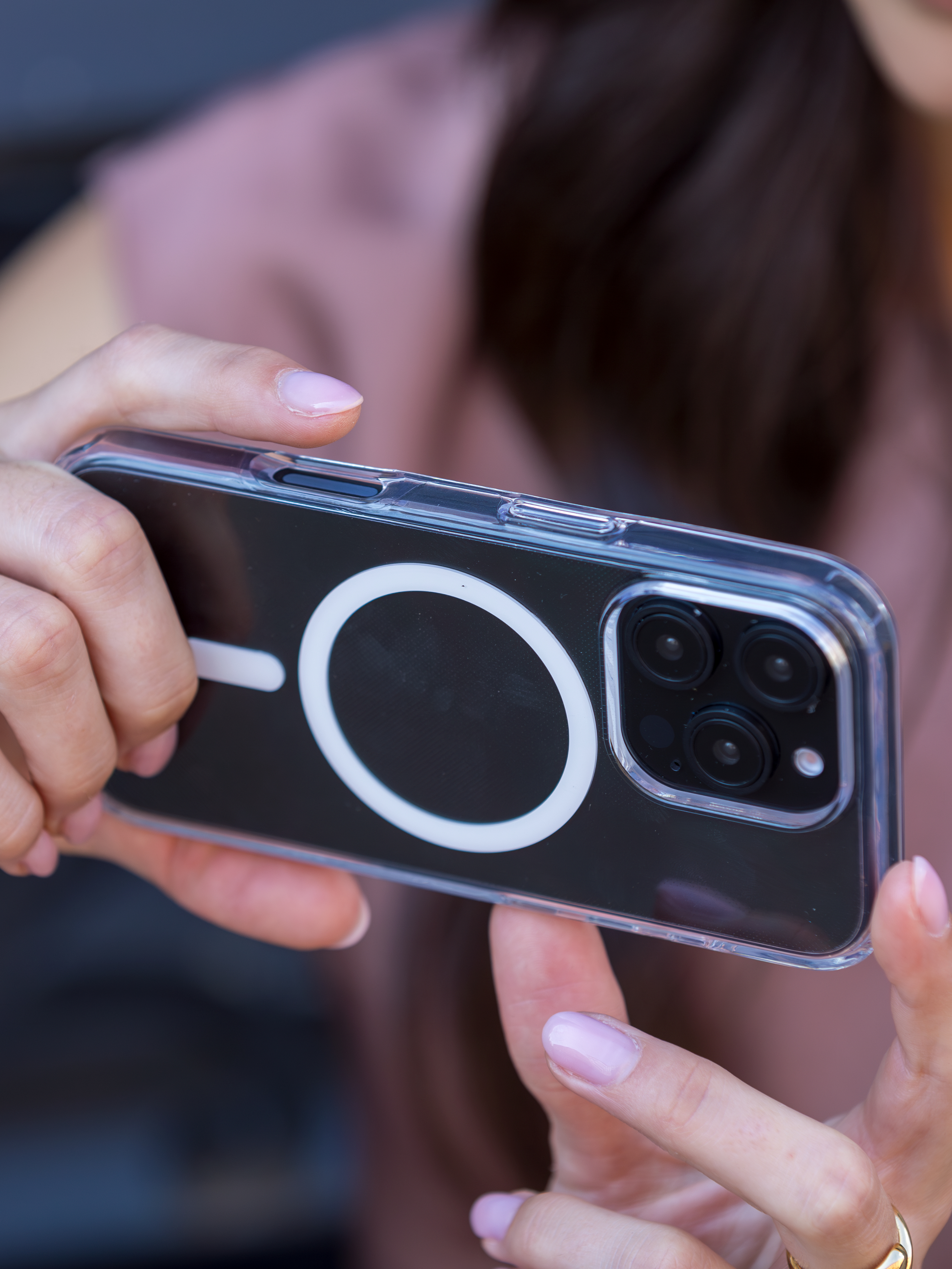 Mano che tiene telefono con custodia trasparente. Il telefono mostra la fotocamera.