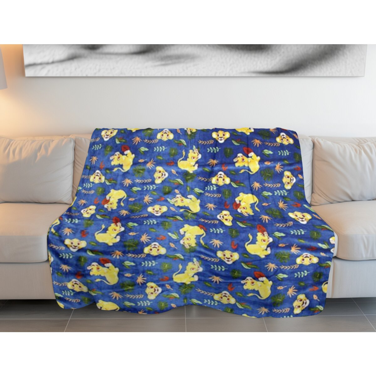Blaue Decke mit gelben Löwen-Cartoons auf weißem Sofa. Hintergrund ist ein Wandgemälde.