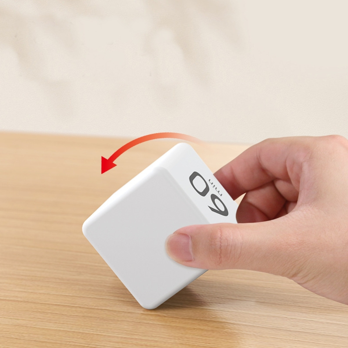 Eine Hand dreht einen weißen Würfel mit der Zahl 60 und einem roten Pfeil.