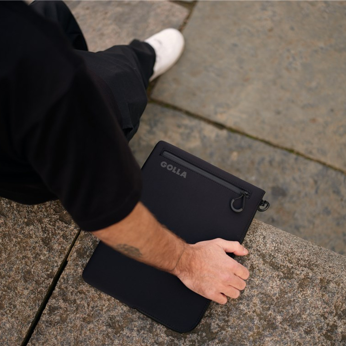 Person hält draußen eine schwarze Golla Laptoptasche.