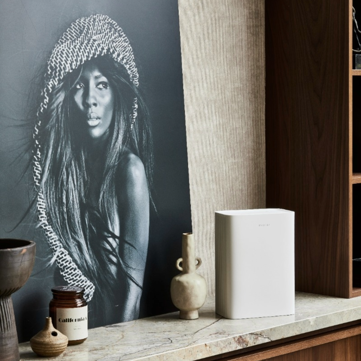 A black and white photo of a woman with a headscarf with a white air purifier.