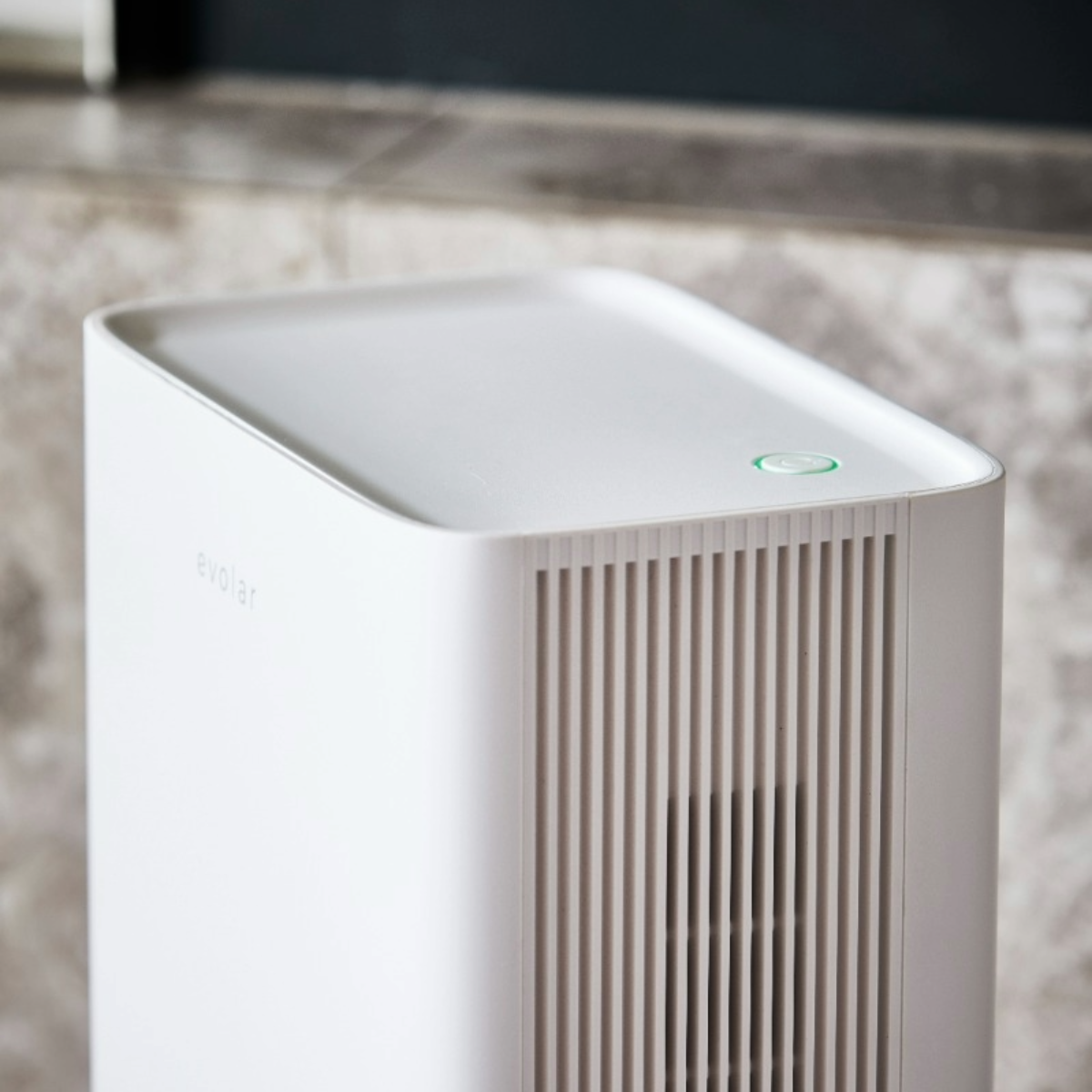 White air purifier with vertical vents and a green power button on top.