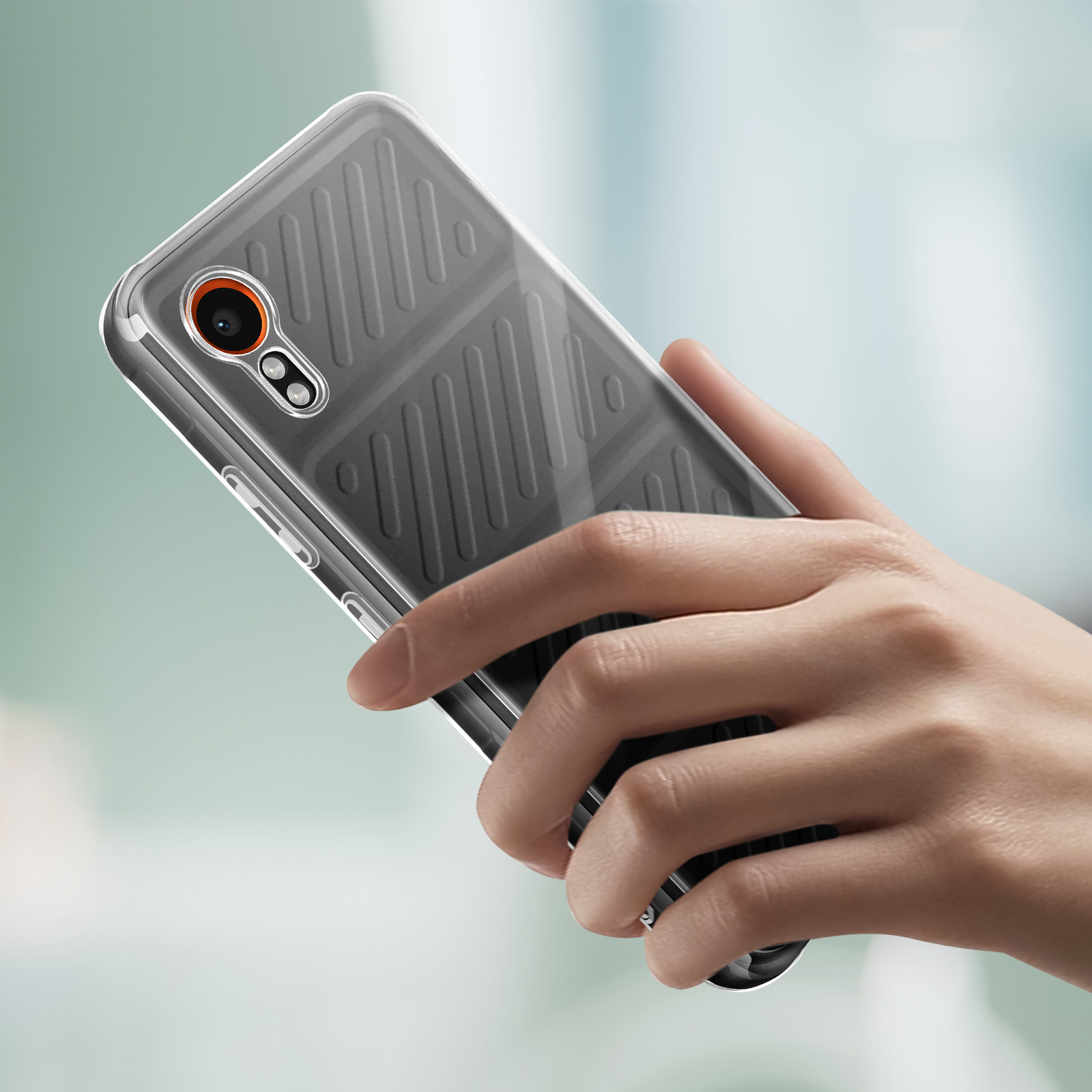 Une main tient un téléphone avec une coque transparente. La coque a un motif sombre au dos.