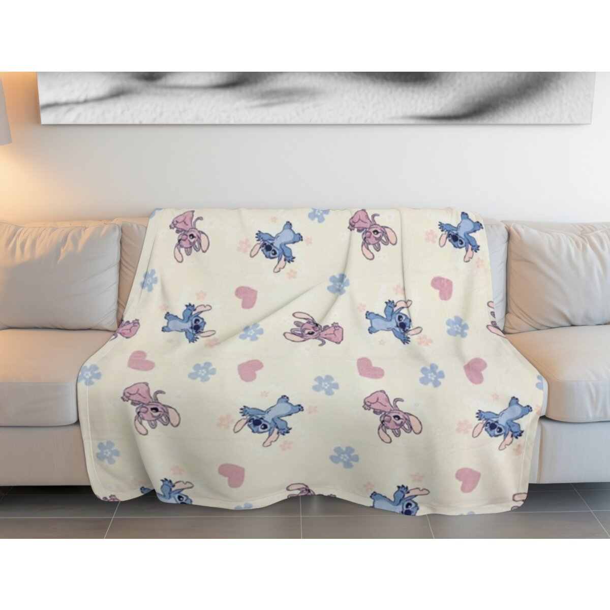 Decke mit Stitch und Angel-Charakteren auf beigem Sofa und weißer Wand.