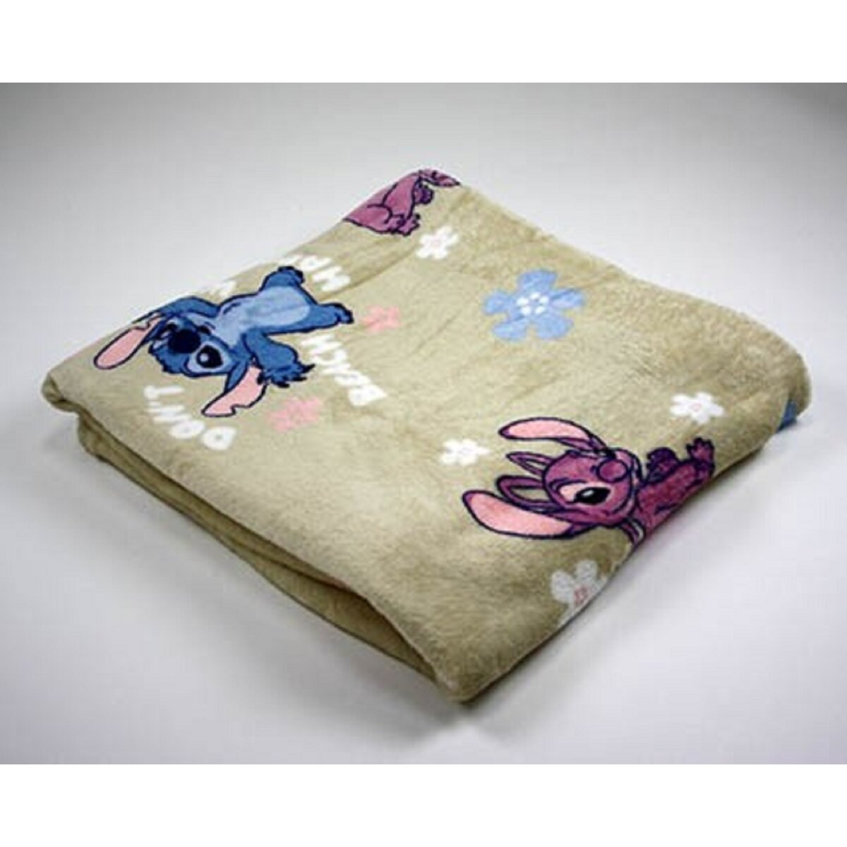 Beige Decke mit Stitch- und Angel-Cartoonfiguren. Gefaltet auf einer weißen Oberfläche.