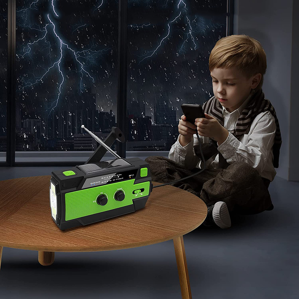 Ein Junge, der ein Telefon benutzt, sitzt in der Nähe eines Radios auf einem Tisch. Blitze zucken draußen am Fenster.
