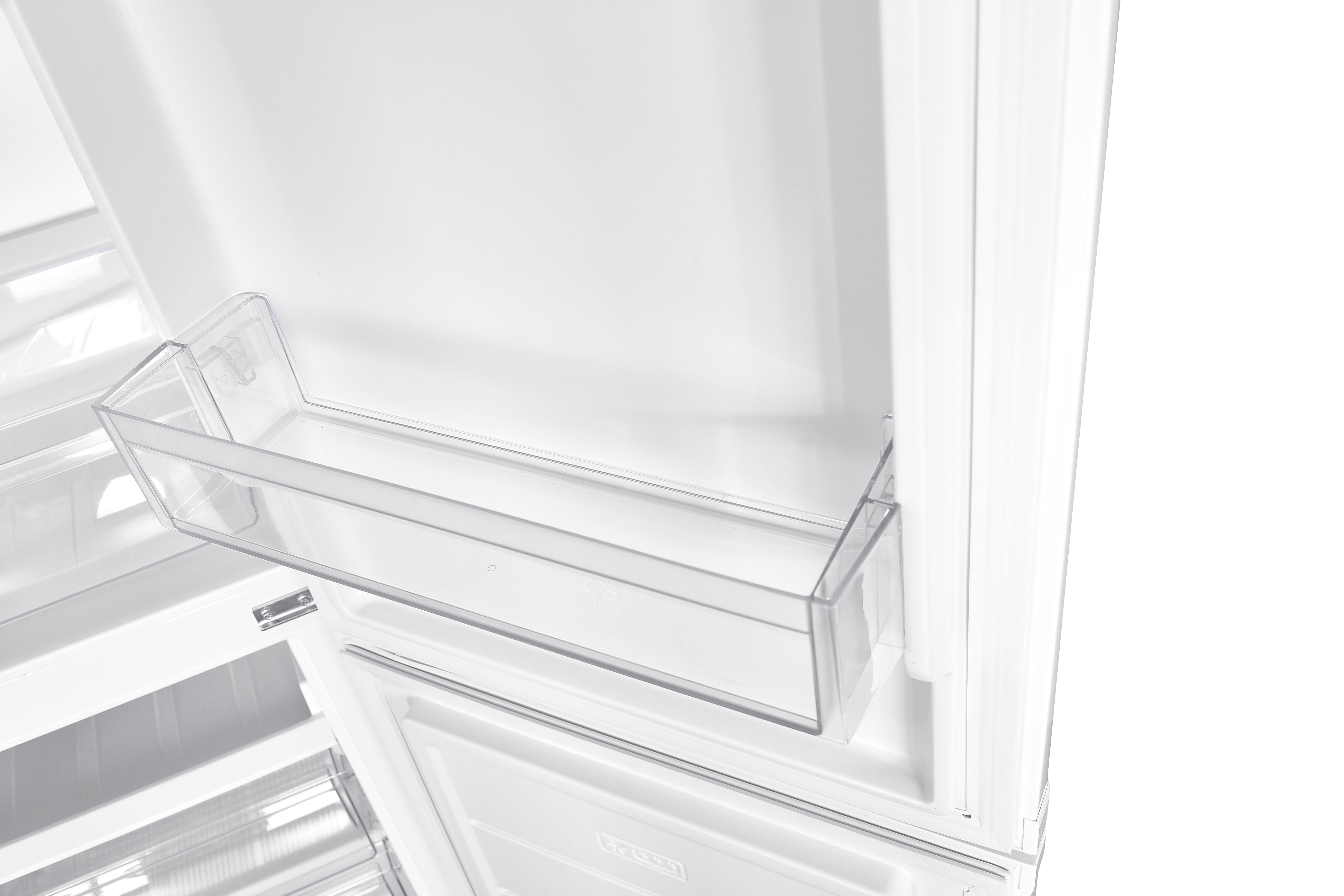 Ein transparentes Kunststoffregal in einem weißen Kühlschrank, das das Innendesign zeigt.