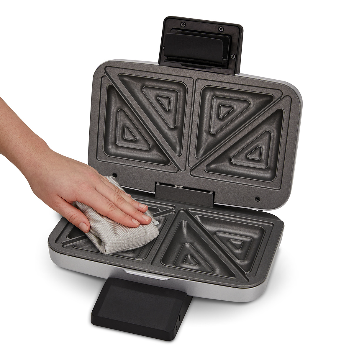 Ręka osoby czyszcząca toster do kanapek. Toster ma cztery sekcje.