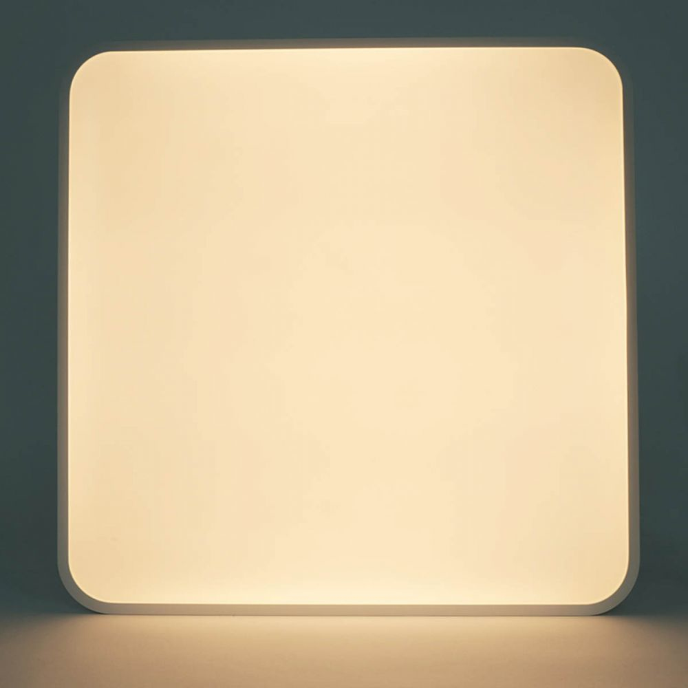 Plafonnier LED carré, cadre blanc aux coins arrondis, émettant une lumière jaune douce.