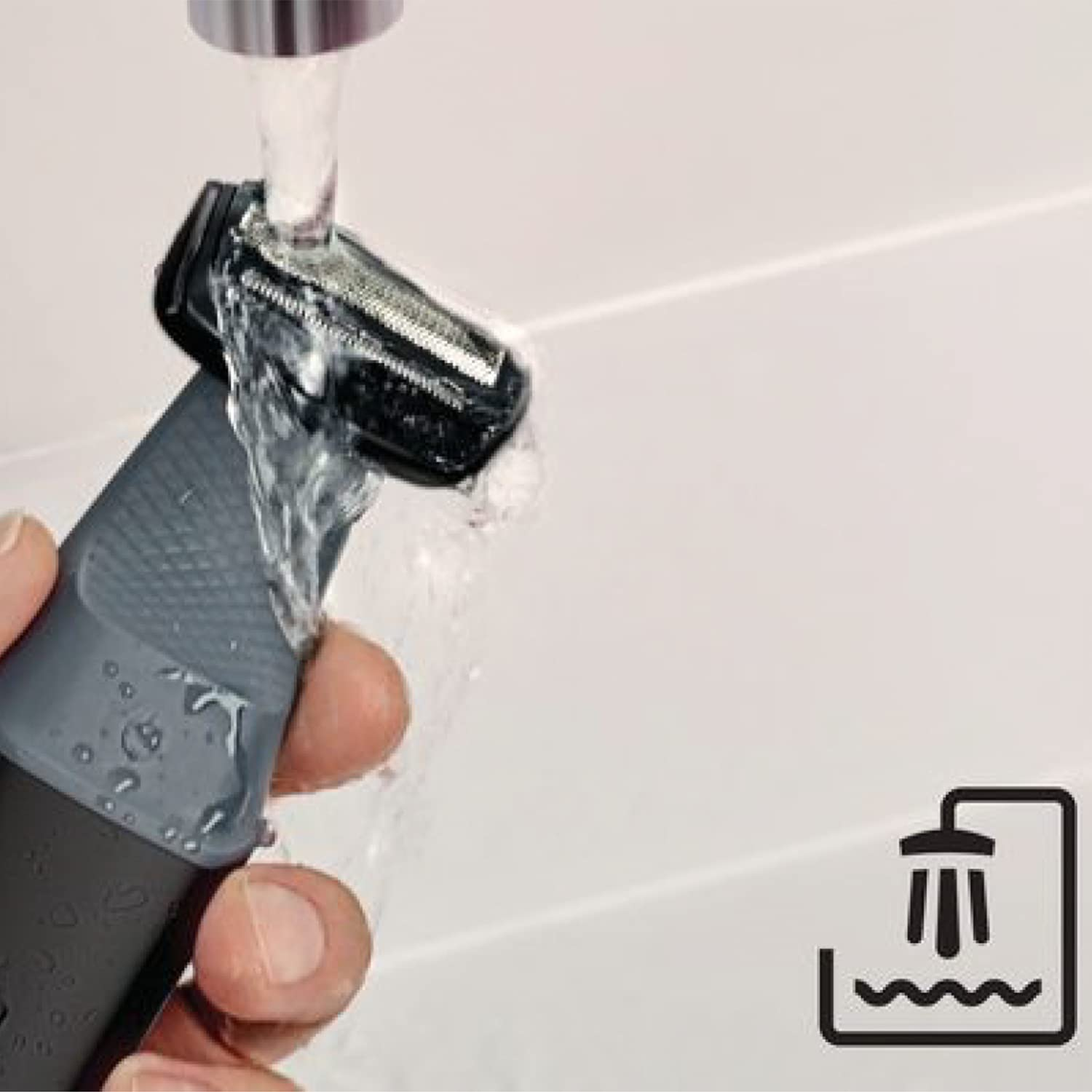 Nahaufnahme einer Hand, die einen grauen Rasiererkopf unter fließendem Wasser hält.