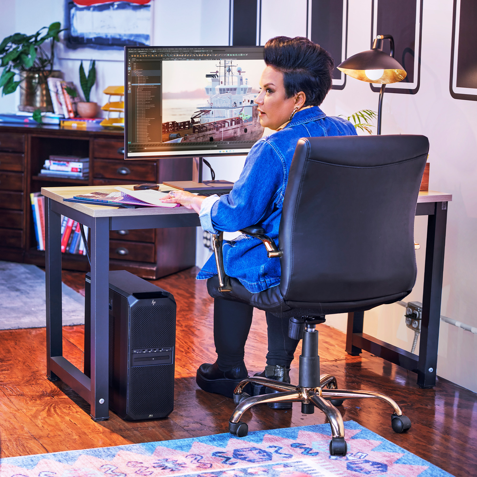 Frau am Schreibtisch, arbeitet am Computer. Der Computer steht neben einem schwarzen Computergehäuse.